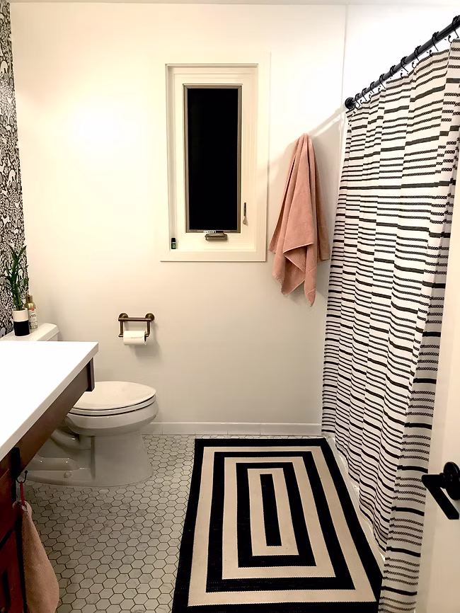 A spacious, accessible bathroom featuring a zero-entry roll-in shower with safety grab bars and a built-in bench, a wall-mounted sink with roll-under clearance, non-slip tile flooring, and a wide doorway designed for mobility and barrier-free access.