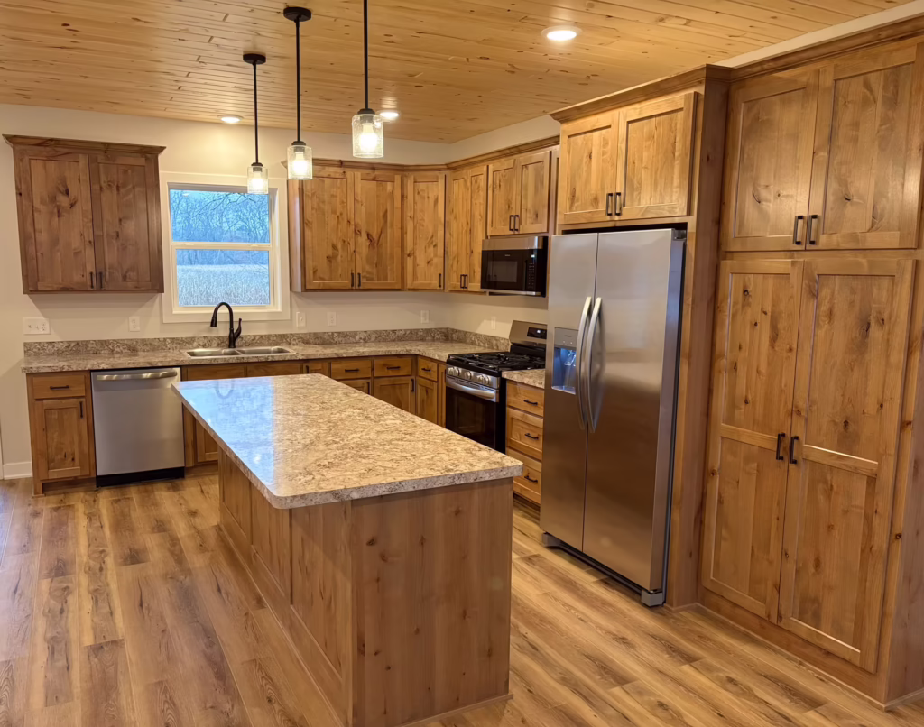 A custom gourmet kitchen featuring a large center island with waterfall quartz countertops, custom shaker cabinetry, high-end stainless steel appliances, a designer tile backsplash, contemporary pendant lighting, and wide-plank wood flooring.